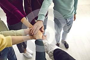 High angle close-up of team of people joining their hands united by a common goal