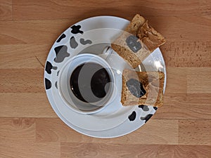 High angle closeup shot of coffee and peanut butter and jelly sandwiches in plate with cow patterns