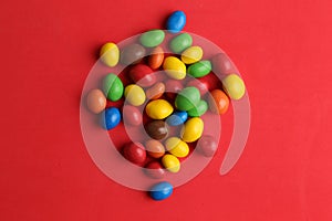 High angle closeup shot of colorful candy balls isolated on a red background