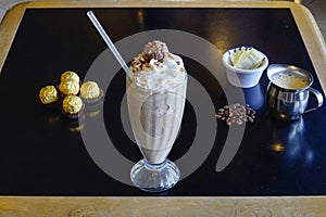 High angle closeup shot of a glass of a chocolate milkshake on a black table