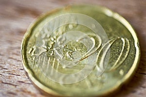 High angle closeup shot of a golden twenty-cent coin on a wooden surface with blurred background