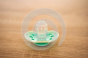 High angle closeup shot of a green baby's dummy on a wooden surface