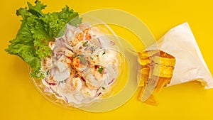 High angle closeup shot of a shrimp dish and chips on a yellow background