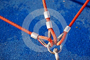 High angle closeup shot of three red ropes attached to a metal holder with a blue background