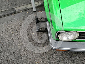 High angle closeup view of the headlights of an old vintage green car