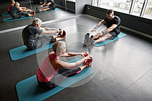 High angle fit people stretching on gym floor