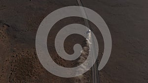 High angle footage of fast moving car on dusty dirt road in volcanic wasteland. Rising clouds of dust. Iceland