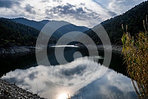 High-angle of lake Sunnet at sunrise with cloudy sky background water reflecting forested mountains