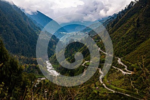 High-angle landscape view with roads on the forested mountain range, cloudy sky background