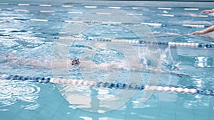 High angle male sportsman floating in crawl style by tracks at swimming pool championship