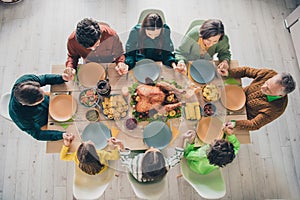 High angle photo of adorable cute family eating holiday turkey sitting table praying holding arms indoors house room