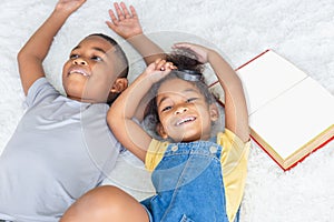 High angle portrait of two children lying down on white floor and looking at camera, Happy sister and brother playing in living