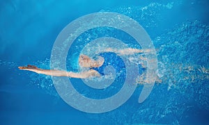 High angle of professional sportswoman swimming in backstroke