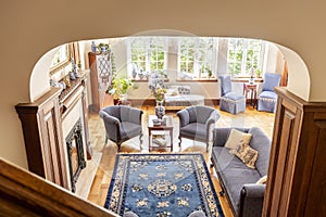 High angle of a rustical living room interior with a blue rug, armchairs, sofa and wooden floor photo