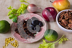 High angle selective focus still life of healthy foods, including dried figs and raisins in a small pink plate