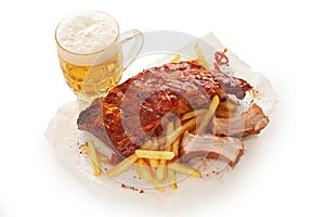 High angle shot of barbeque pork spareribs and French fries served with a glass of lager beer