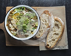 High angle shot of a bowl of soup and vegetables and loaves of bread