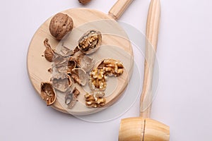 High angle shot of the broken walnuts on the wooden cutting board with the wooden mallet