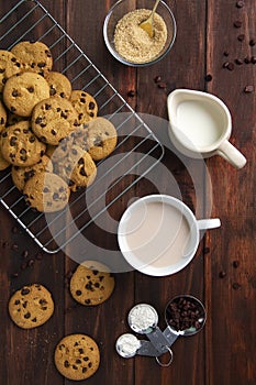 High angle shot of Chocolate chip cookies, milk in a jug and coffee in a cup on a wooden table