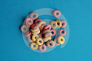 High angle shot of colorful fruit loops isolated on a blue surface