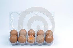 Top view of cracked fresh egg and whole eggs with bright yolk in plastic tray for eggs.