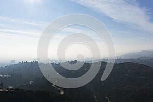 High angle shot of curvy roads in the middle of trees on the mountains under a blue sky