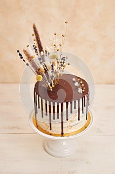 High angle shot of delicious Boho cake with chocolate drip and flowers with golden decorations
