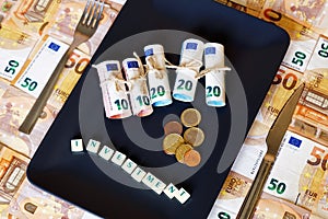 High angle shot of Dinero money bills in a plate with a fork and white cubes spelling Investment