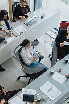 High-angle shot of a diverse group of employees engaged in a collaborative work setting in a contemporary office.