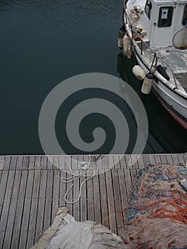 High angle shot of fishing nets on an old wooden pier and a rusty boat in the water