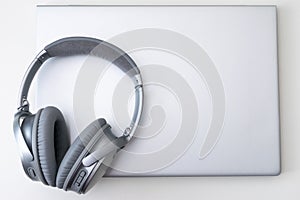 High angle shot of a gray headphone on a gray laptop isolated on a white background