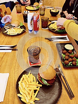 High-angle shot of a group of friends enjoying fast food meal with hamburgers and fries