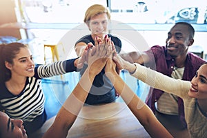 Alone we are smart, together we are brilliant. High angle shot of a group of happy friends high fiving each other.