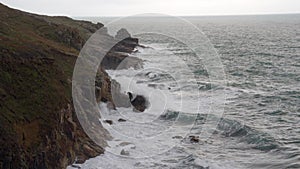 High-angle shot of high tide waves swashing some cliffs in Cornwall, South West England