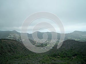 High angle shot of houses in the middle of a mountainous scenery partially covered in fog in Hawaii