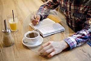 High angle shot of a male readin a book with coffee and a juice on the table