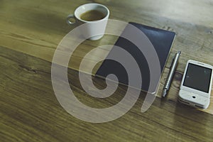 High angle shot of a notebook with a silver pen, a cup of coffee and white cellphone