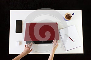 High angle shot of a person working at a work desk with a laptop, a cup of coffee, and mobile phone