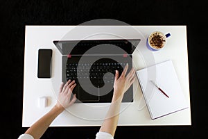 High angle shot of a person working at a work desk with a laptop, a cup of coffee, and mobile phone