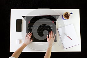 High angle shot of a person working at a work desk with a laptop, a cup of coffee, and mobile phone