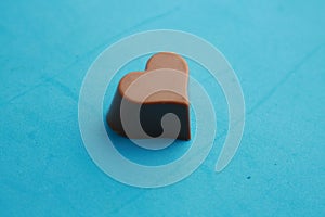 High angle shot of a piece of heart-shaped chocolate isolated on a blue surface