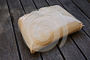 High angle shot of a plastic bag full of flour on a wooden surface