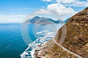 High angle shot of a road on the side of a mountain coast with blue ocean water