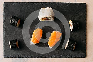 High angle shot of rolled and cut delicious  salmon and rice sushis on black board