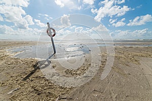 High angle shot of a sandy shore with an  direction sign under the bright calm sky