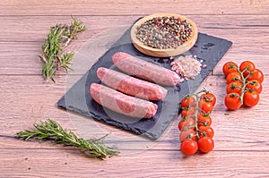 High angle shot of sausages near tomatoes, a bowl of peppercorns and a lot of Himalayan salt