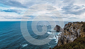 High angle shot of the sea near the mountain under a cloudy sky in Cabo Penas, Asturias, Spain