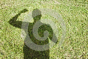 High angle shot of the shadow of a person stretched on a grass-covered field