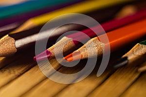 High angle shot of sharpened color pencils on a wooden surface under spotlight