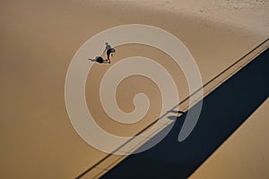 High angle shot of a single surfer walking on smooth sand at a beach